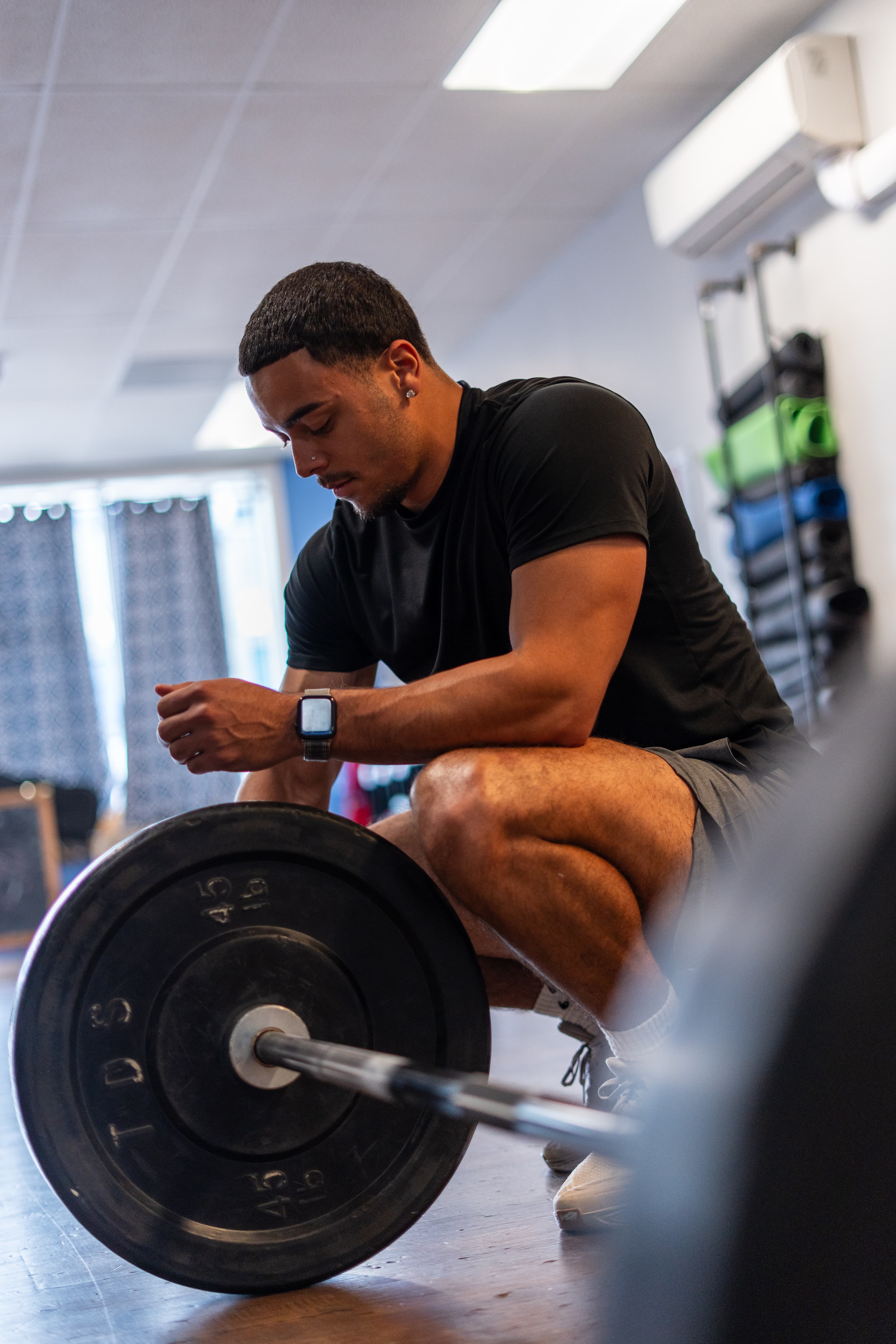Kai Tranchant resting beside a barbell in the gym